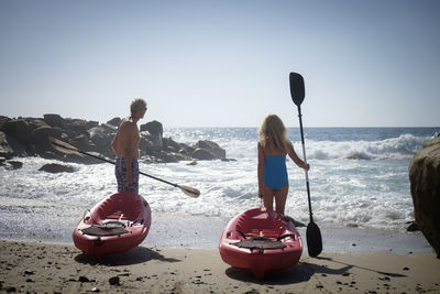 Senior couple pushing canoes by the sea