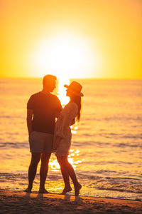 Silhouette woman standing at beach during sunset