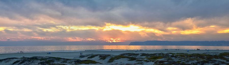 Scenic view of sea against dramatic sky during sunset