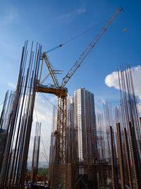 Low angle view of cranes against buildings