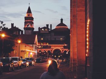 People on illuminated street amidst buildings in city at night