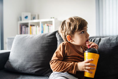 Rear view of boy sitting on sofa at home