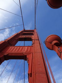 Low angle view of suspension bridge against blue sky