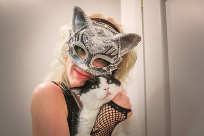 Portrait of young woman wearing mask holding cat