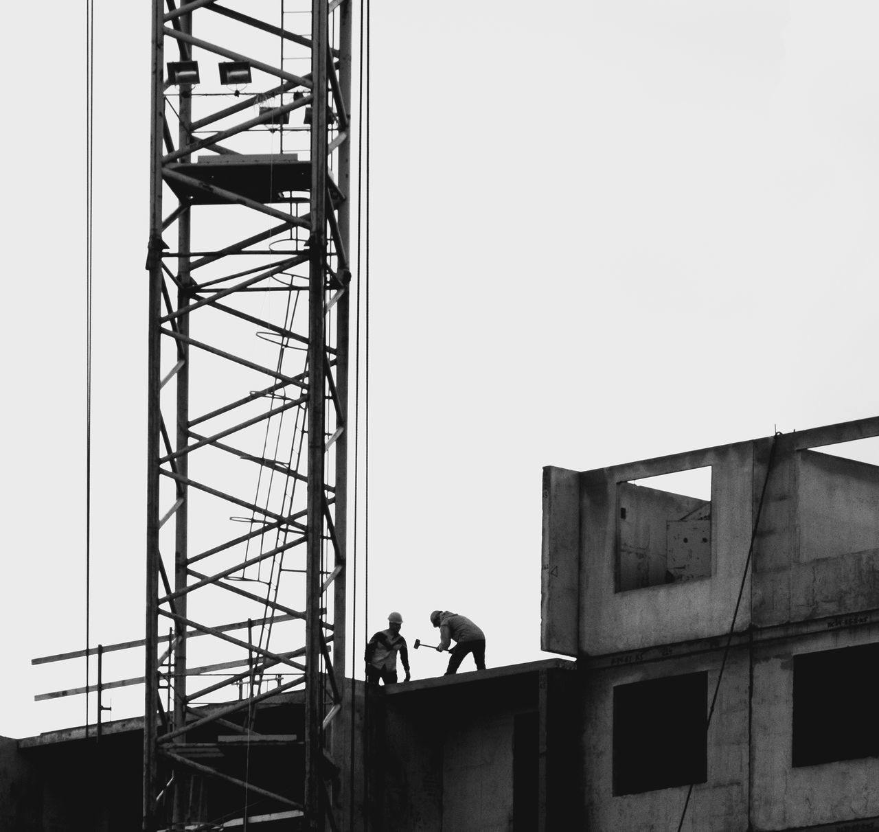 LOW ANGLE VIEW OF MAN WORKING AT CONSTRUCTION SITE AGAINST SKY