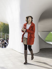 Curly woman in red duffle coat. student with laptop. freelancer. modern lifestyle.