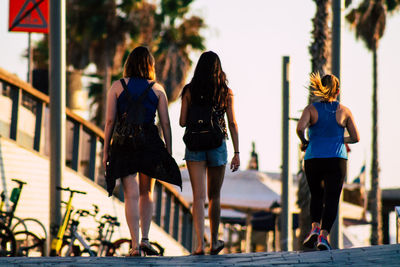 Rear view of women walking on railing in city