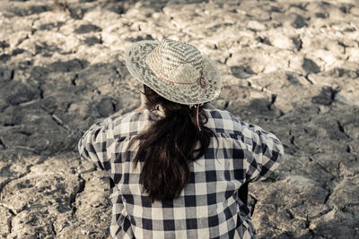 Rear view of woman sitting on barren field