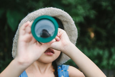 Close-up portrait of woman holding sunglasses against blurred background