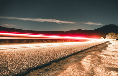 Light trails on road against sky at night