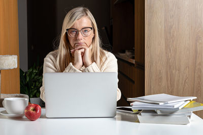 Woman using phone while sitting on table