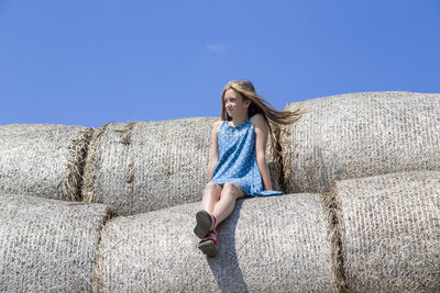 Full length of woman sitting against blue sky