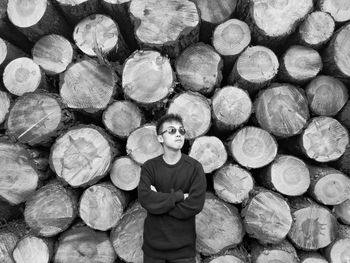 Man standing against stack on logs