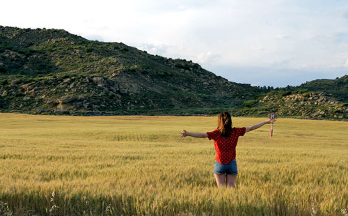 Rear view of woman standing on field against sky