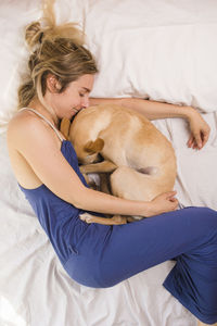 Midsection of woman with dog lying on bed at home