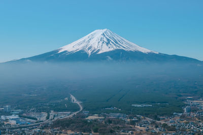 Aerial view of snowcapped mountain against blue sky