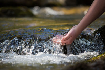 Person touching water splashing on rocks
