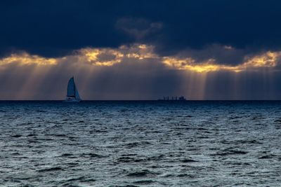 Sailboat sailing on sea against sky during sunset