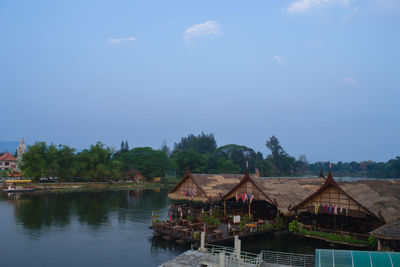 Houses and trees by lake against sky