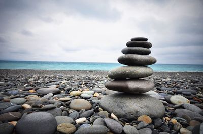 Stack of pebbles on beach against sky