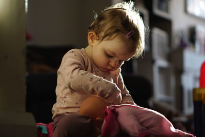 Cute girl playing with doll at home