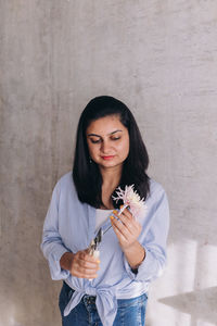 Portrait of smiling woman using florist scissor to cut  a flower stem 