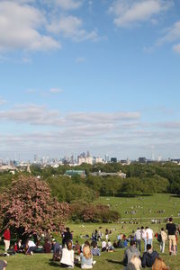 Group of people relaxing on landscape against sky