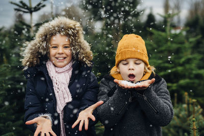 Brother and sister having fun with snow before christmas