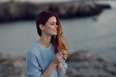 Young woman standing against sea