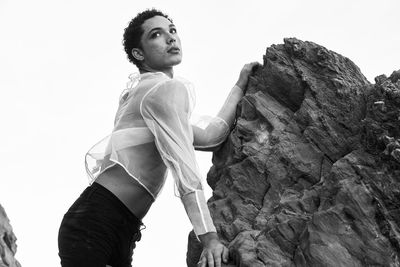 Young male with  androgynous look shot outdoor in black and white with rocks in background.