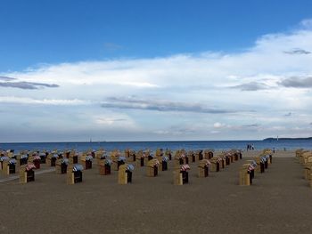 Hooded chairs arranged at beach against sky