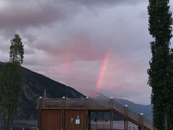 Rainbow over building and mountains against sky
