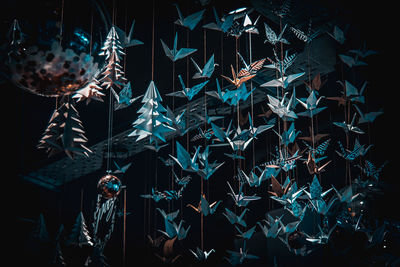 Lots of origami swans hanging from the roof, seen from underneath in a softly illuminated room