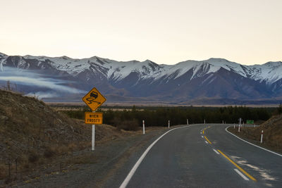 Road sign by mountains against sky