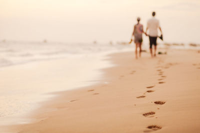 Rear view of couple walking at beach