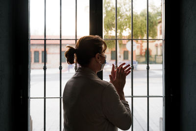 Rear view of woman looking through window