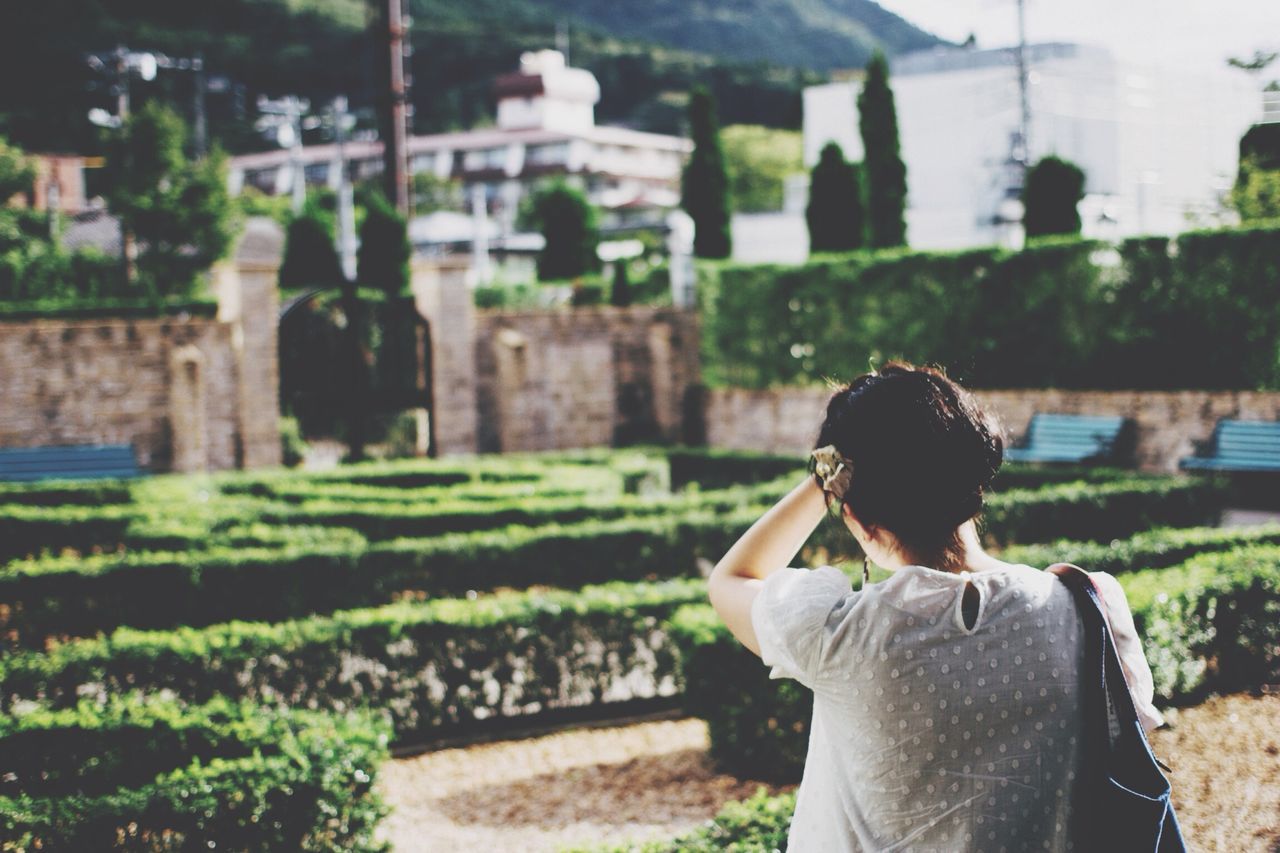 rear view, focus on foreground, lifestyles, leisure activity, casual clothing, person, men, built structure, standing, grass, architecture, building exterior, sitting, waist up, day, field, three quarter length, outdoors