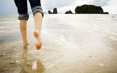 A young woman walks alone on a beach