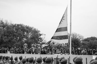 Group of people by flags against clear sky