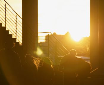 Rear view of people on building against sky during sunset