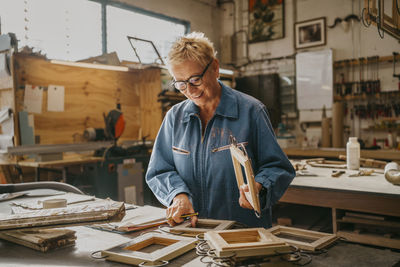 Smiling senior carpenter examining frames at workshop