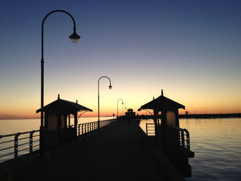 Silhouette built structure by sea against clear sky