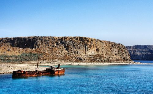 Scenic view of rocks in sea against clear blue sky