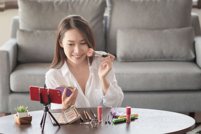 Portrait of a smiling young woman sitting on table at home