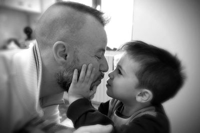 Side view of father kissing son at home