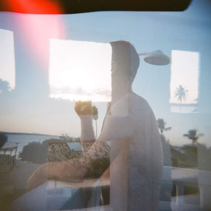 REFLECTION OF MAN PHOTOGRAPHING ON MOBILE PHONE AGAINST SEA