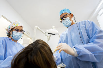 Dentist with nurse treating woman at clinic