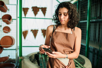 Female potter using mobile phone in pottery shop