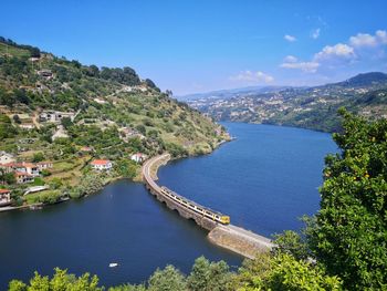 High angle view of river amidst trees against blue sky