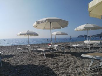 Beach umbrellas by sea against clear sky